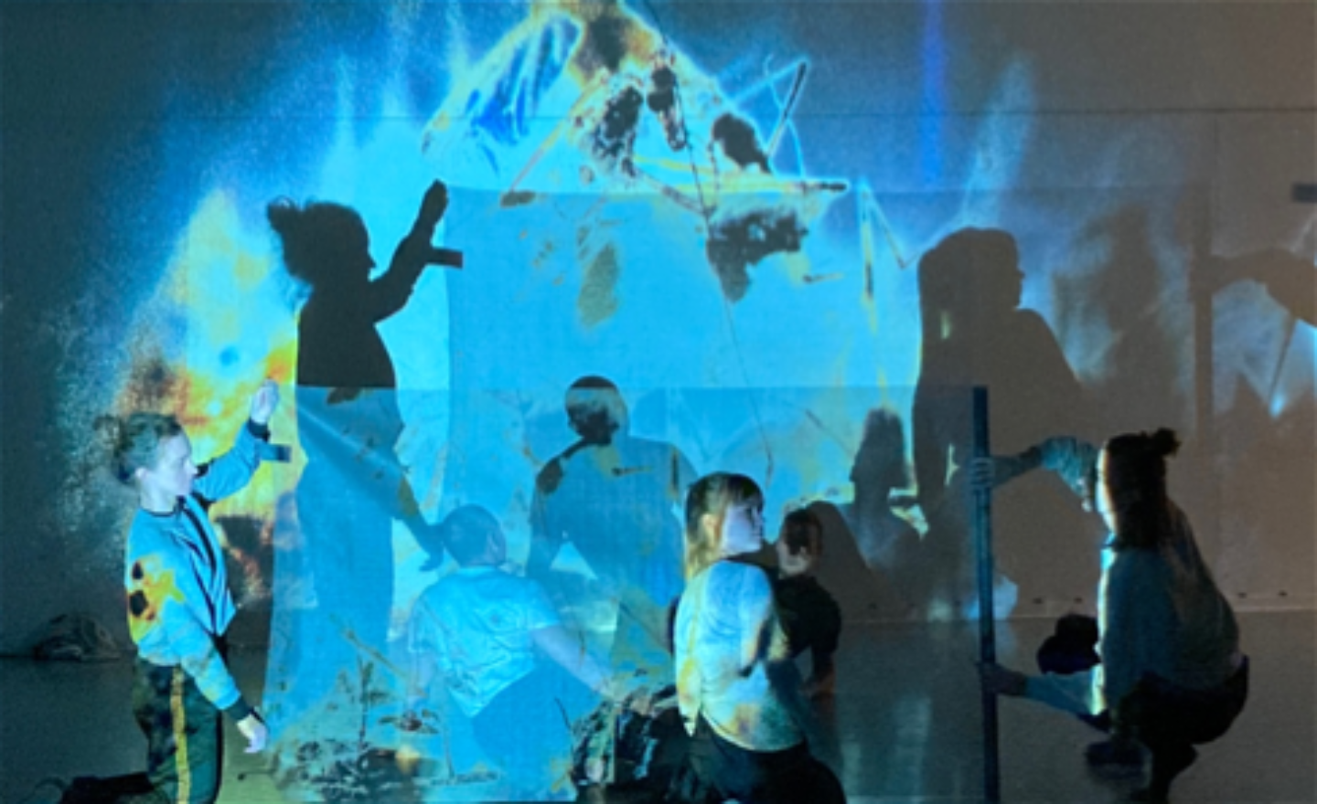 repetitionsbild: 5 dansare och deras skuggor i en blå projektion med gul-vit-bruna insekter