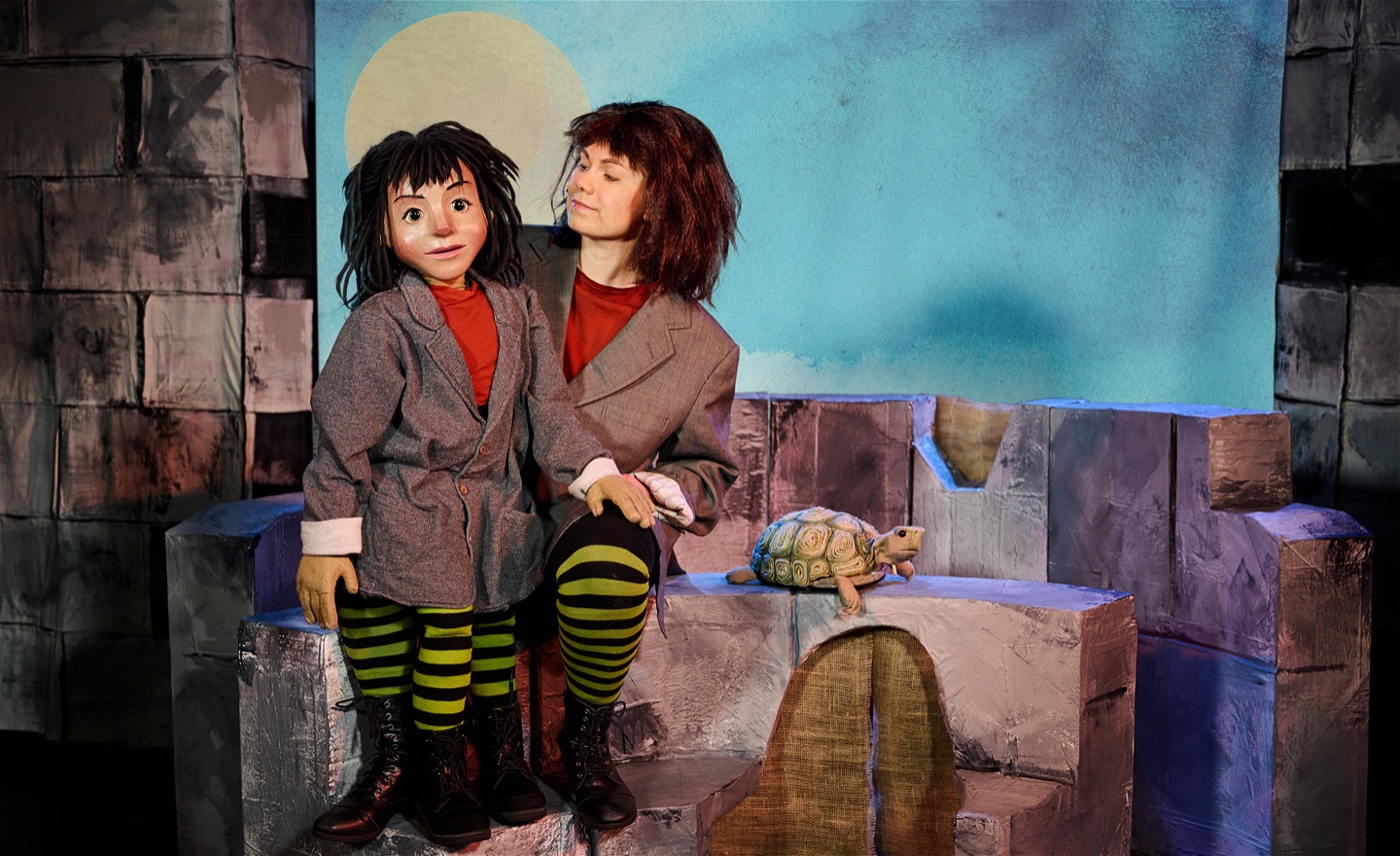 Föreställningsfoto från MOMO, föreställande Momo både som docka och som gestaltad av skådespelare Anna-Riina Virtanen