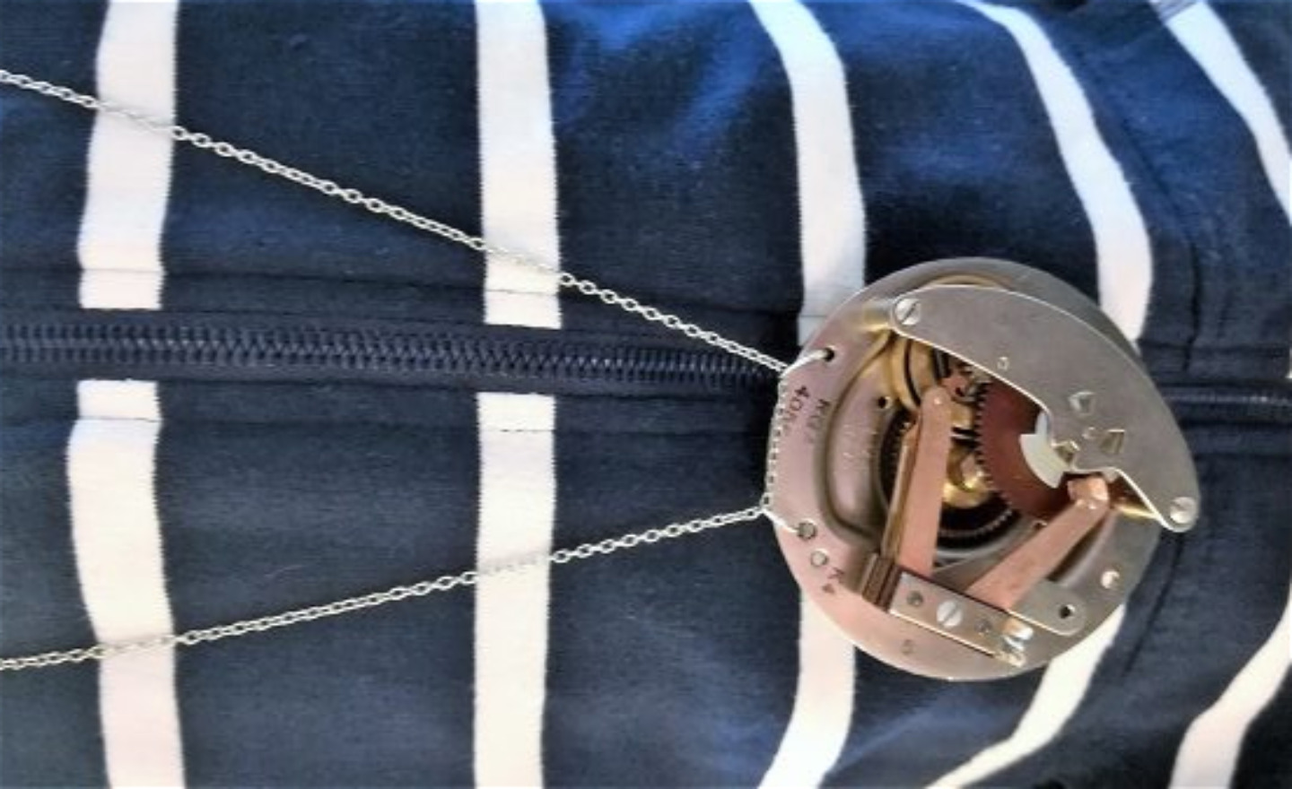 Ett smycke av metallbitar mot bakgrund av en blå - och vitrandig tröja