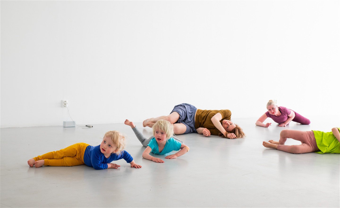 Barn och vuxna rullar tillsammans på golvet.