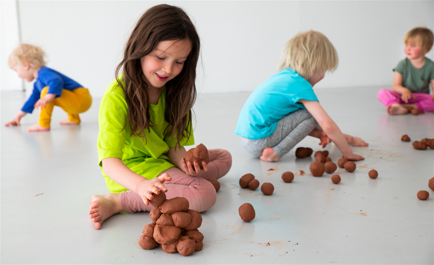 Barn bygger en skulptur av leran formad till bollar.