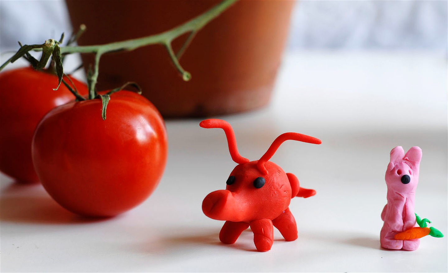 Två fantasifigurer gjorda i lera och två tomater.