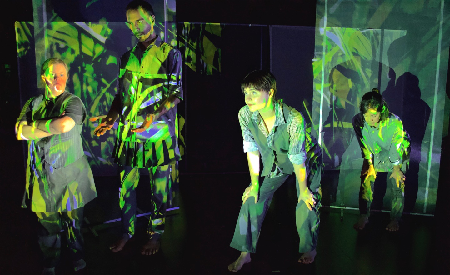 Fyra dansare står i olika positioner täckta av gröna projektioner, de står som ibland stora grässtrån