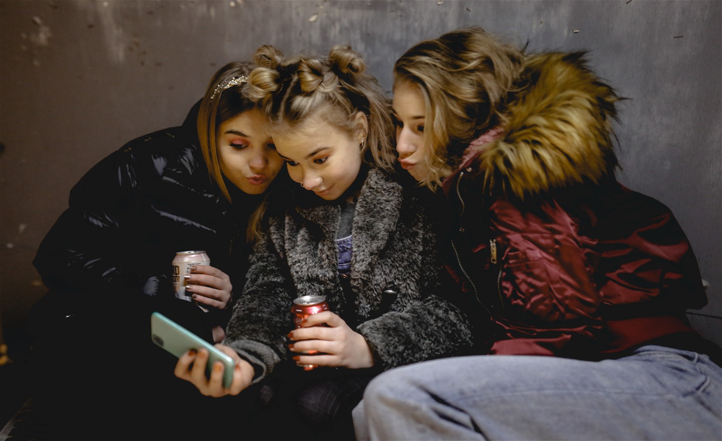 Tre flickor tittar in i telefonens kamera och plutar med munnarna.