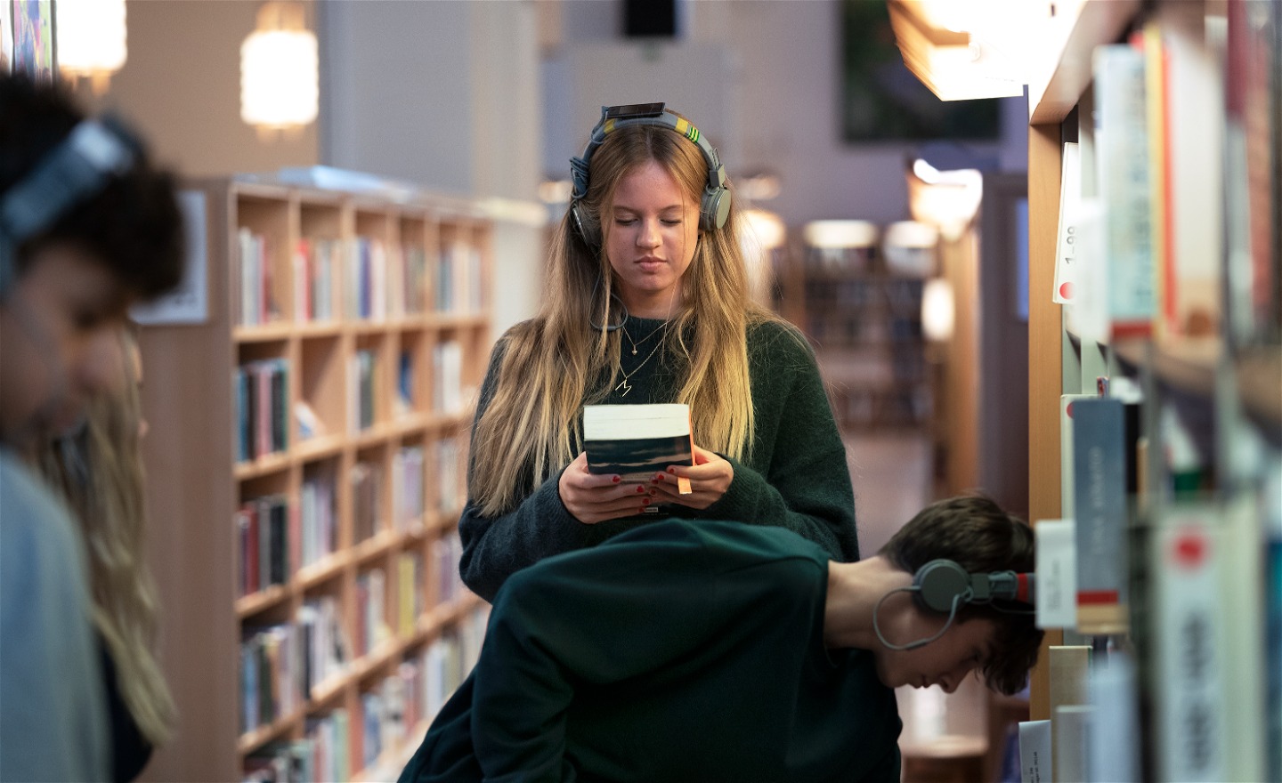 En person med hörlurar håller i en bok