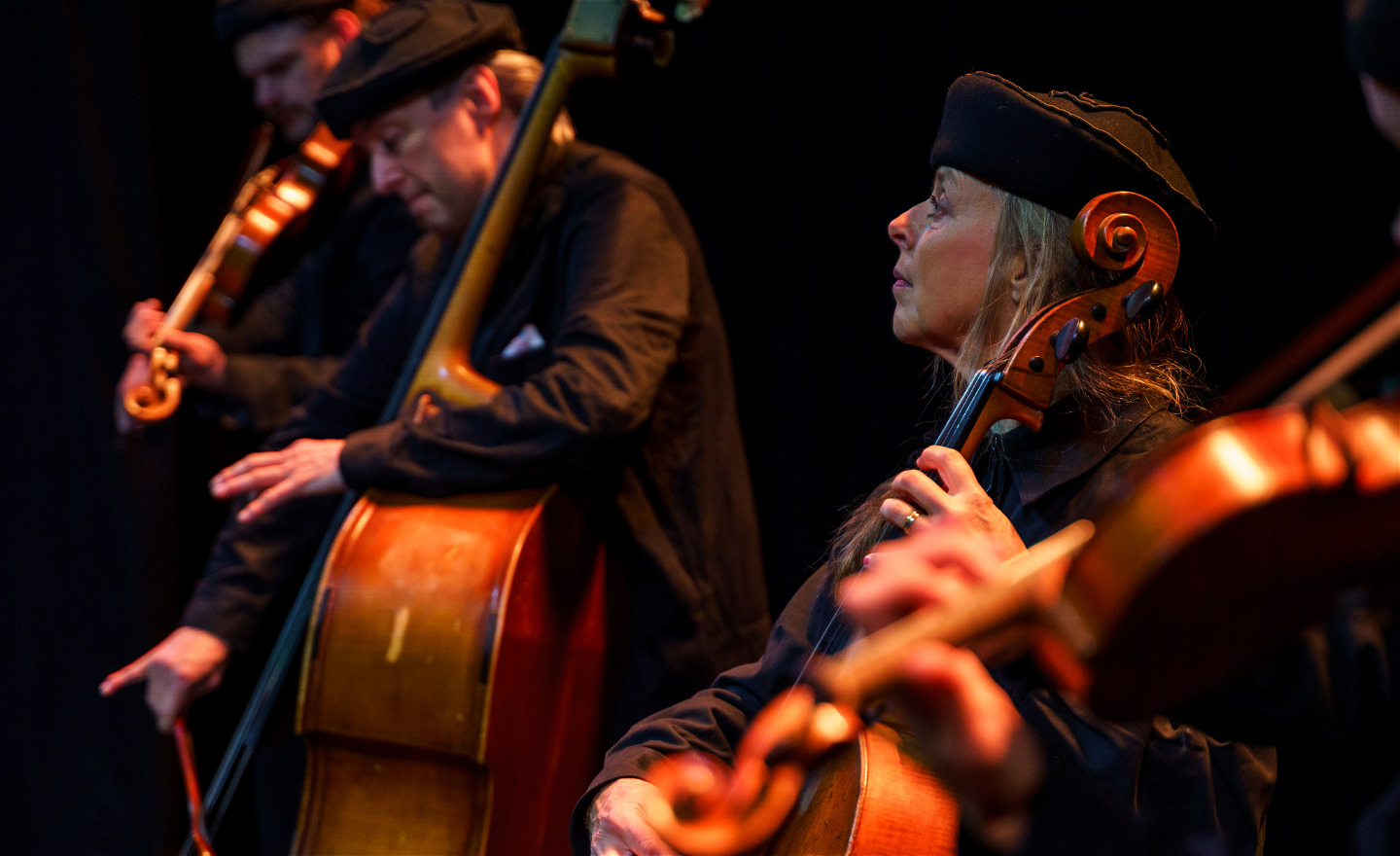 Tre familjemedlemmar Stråke spelar koncentrerat på sina instrument.