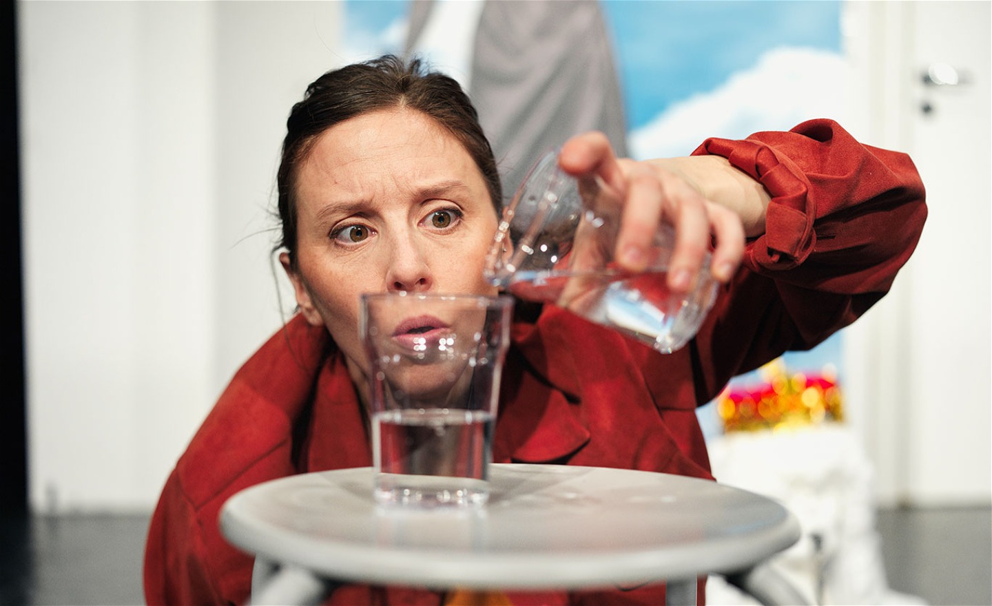 person i röd skjorta fördelar vatten i två glas.