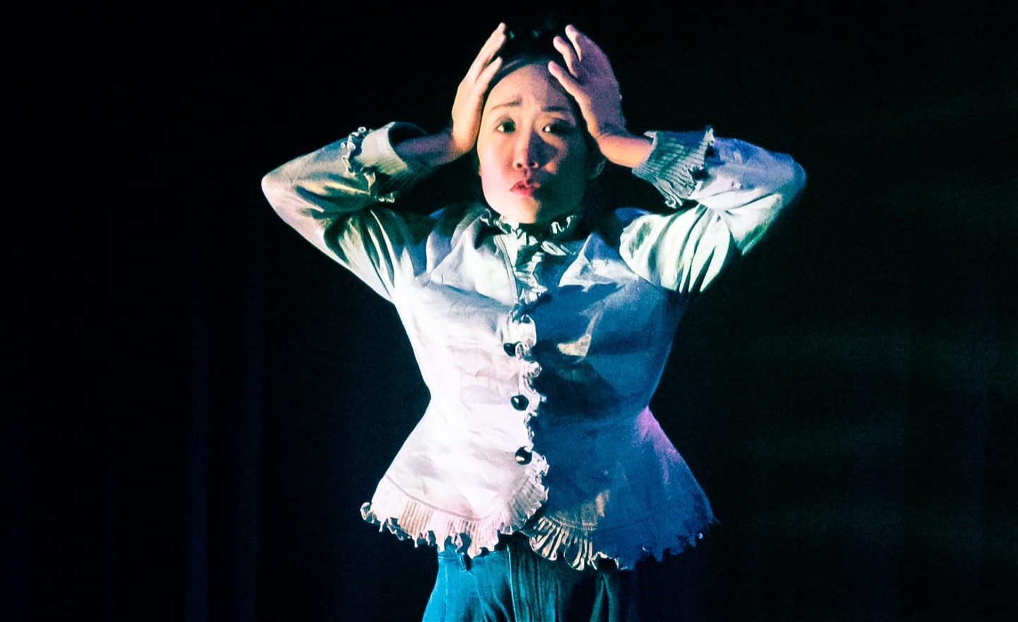 En kvinna som gör en upprörd gest med händerna på huvudet.