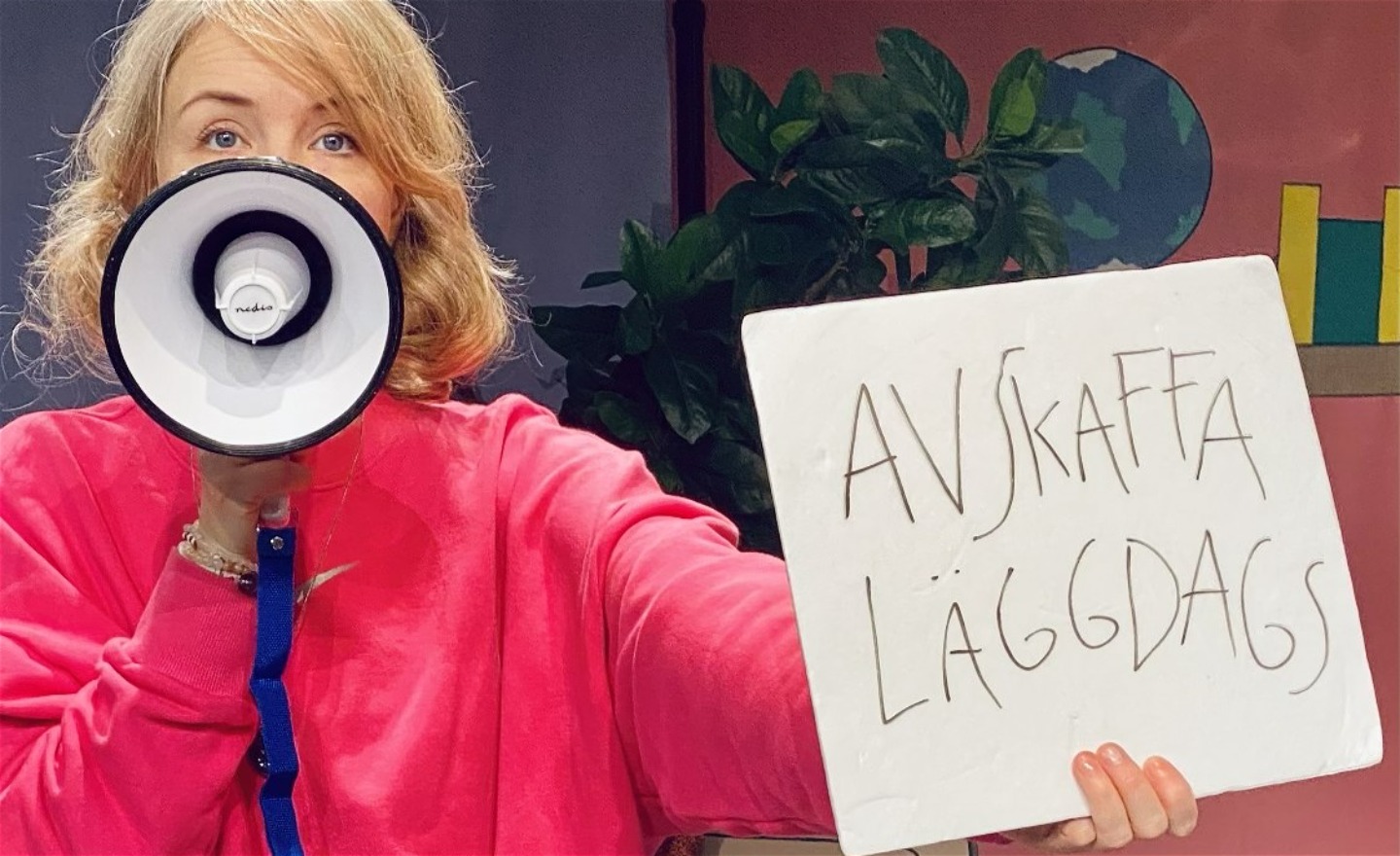 En flicka med en megafon håller upp en skylt det står 