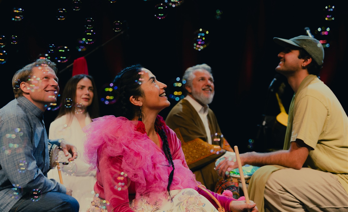 En bild på gruppen Golbangs bandmedlemmar när de sitter på huk och tittar upp mot såpbubblor.