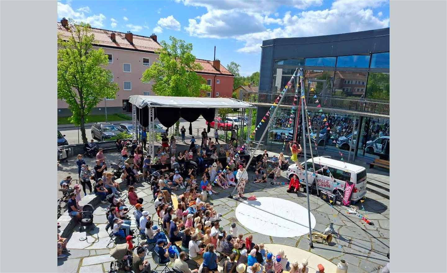 cirkus spektakel på ett torg där man ser publik och en artist i en luft-ring