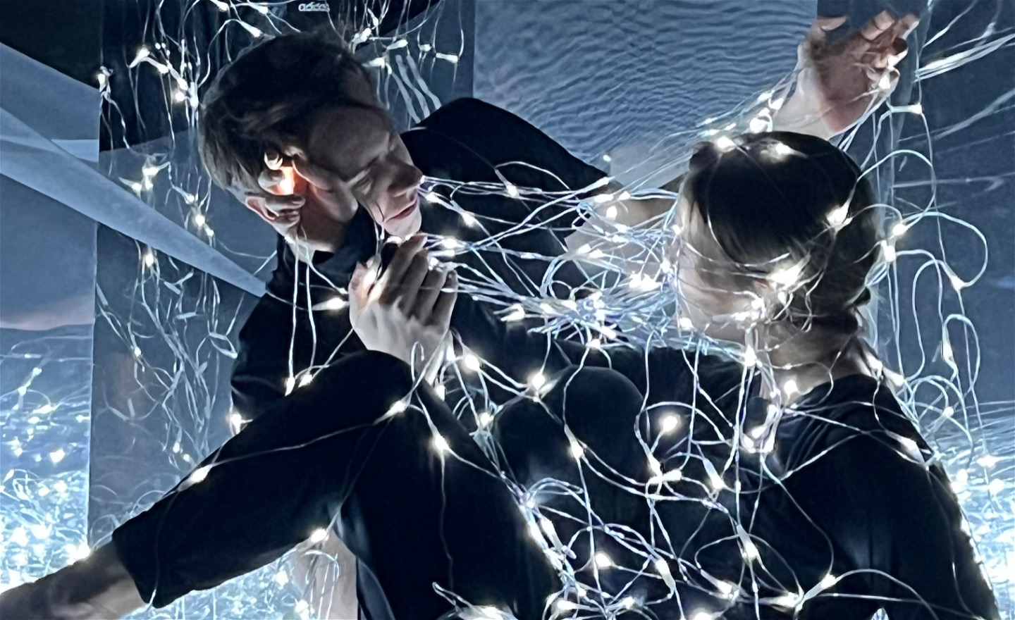 Två dansare vända mot varandra täckta av ljusnät