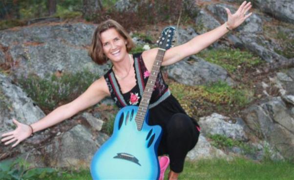 Barnrytmikledaren Charlotte Wihk med en blå gitarr. 