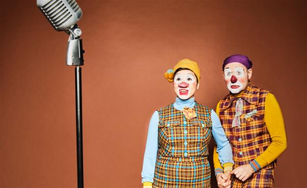 Två clowner håller hand när de står på scenen