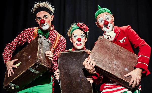 Tre glada clowner bär på sina resväskor