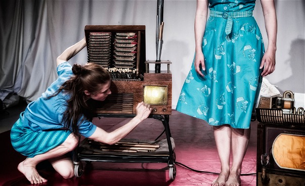 Två kvinnliga dansare på en scen, varav  en lyssnar på en gammal radio.