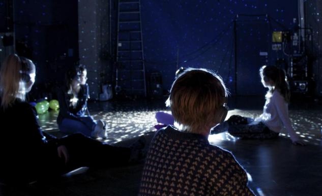 Barn sitter i ett mörkt rum med hörlurar på sig