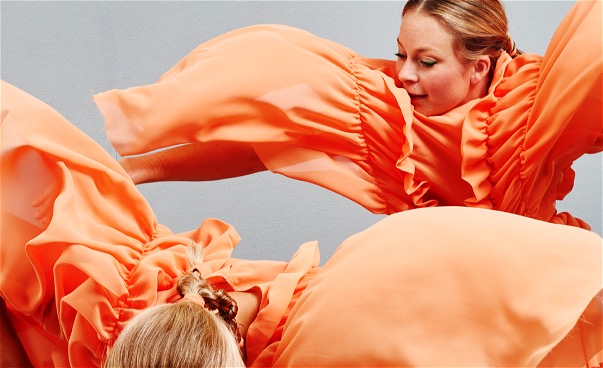 Närbild två dansare i orange flygande dräkter