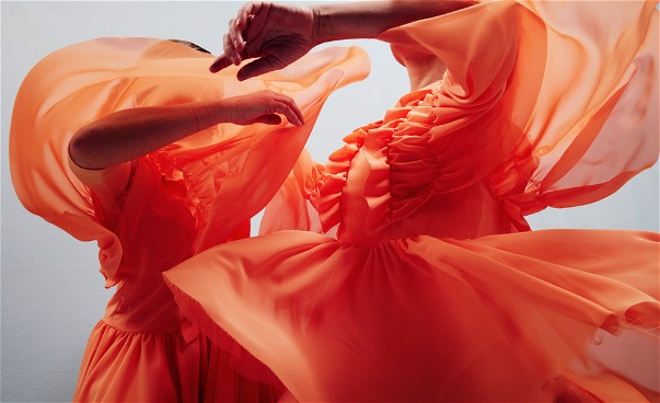 Närbild två dansare i orange flygande dräkter